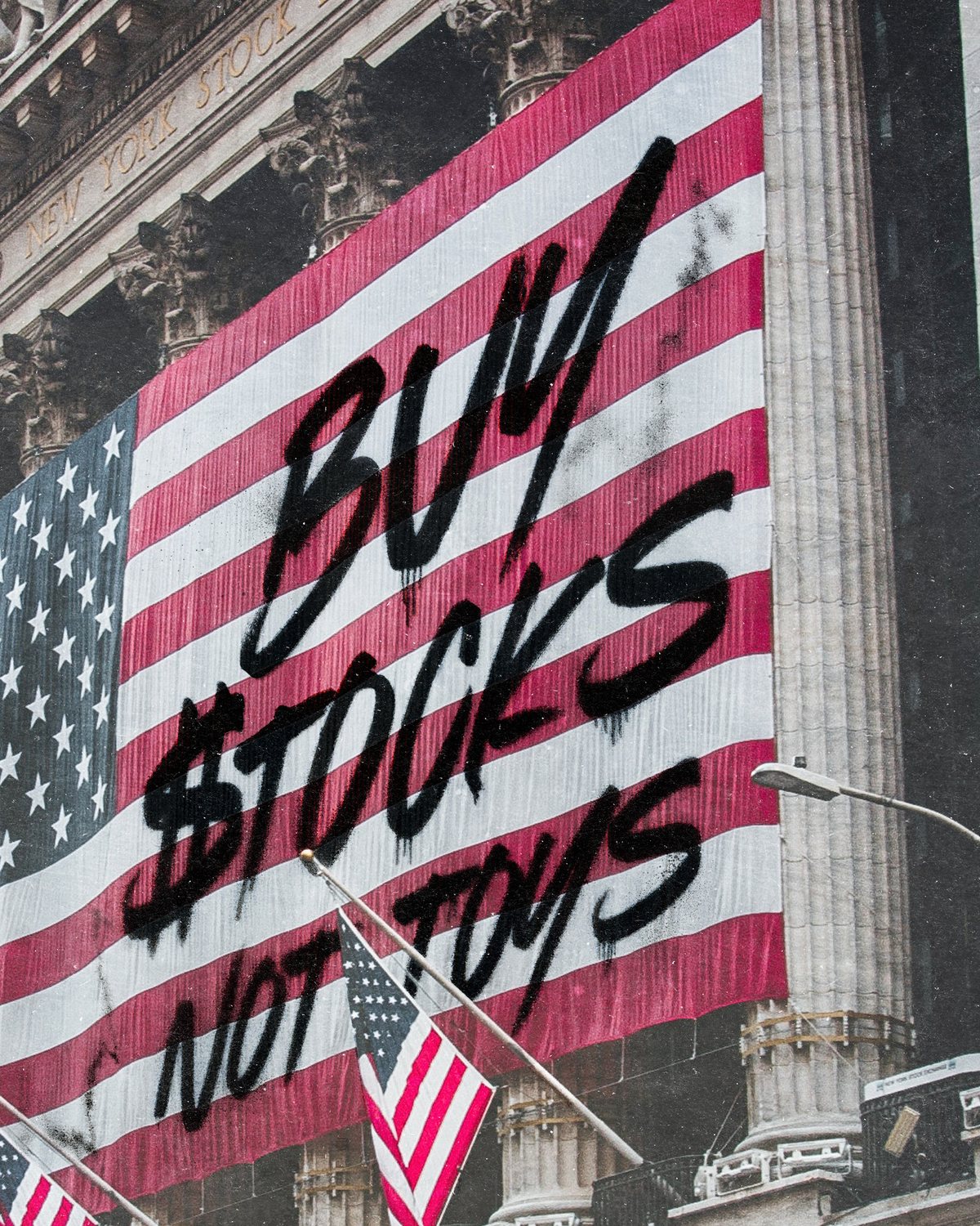Ausschnitt aus dem Motiv: der schwarze Schriftzug Buy Stocks Not Toys auf der Flagge an der Börse